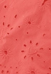 Koraal stof met geborduurde bloemen en harten, met uitgesneden patronen en textuursteekwerk. Zacht, lichtgewicht materiaal.