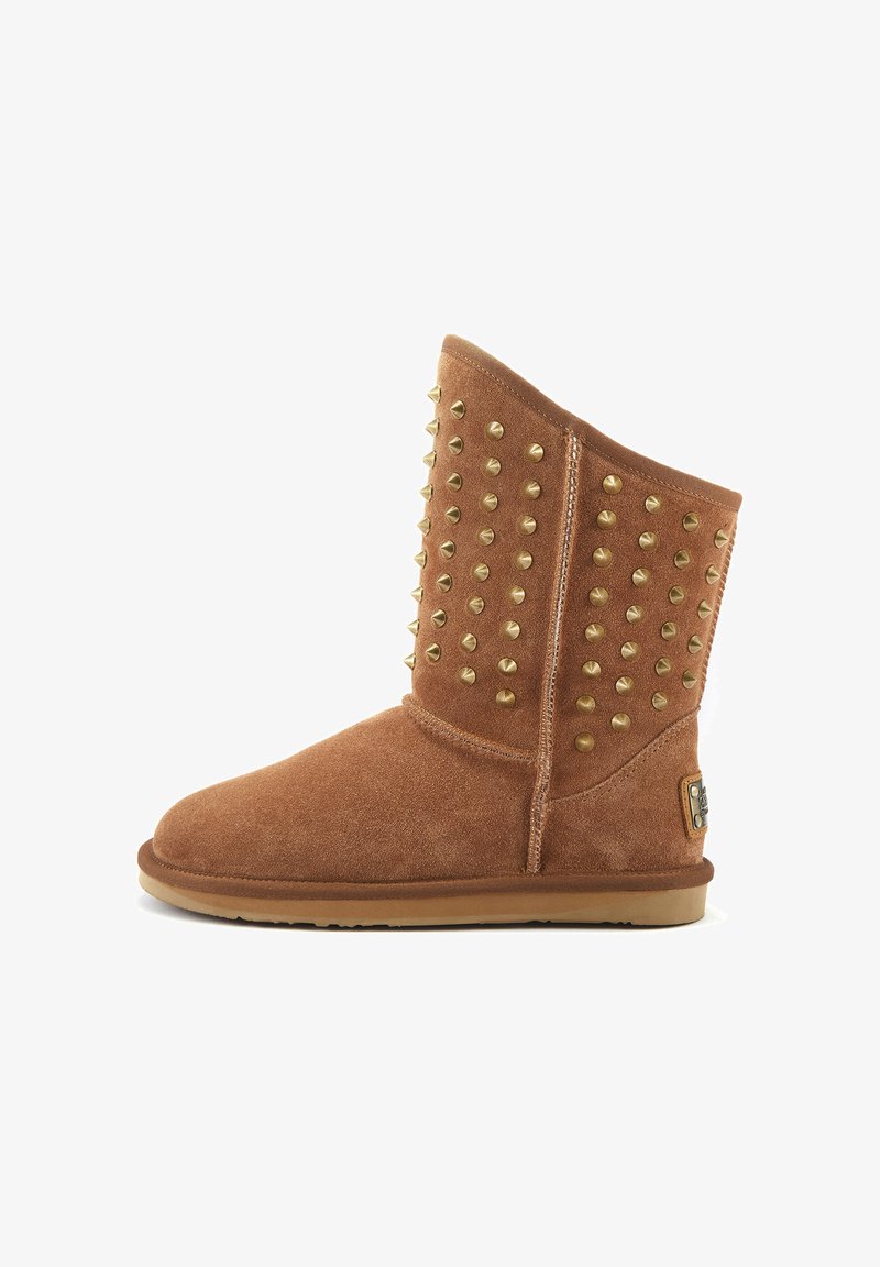 Botas de tobillo de ante en color marrón con acentos de tachuelas doradas, puntera redondeada y suela plana de goma. Presentan una cremallera lateral y un detalle con logo.