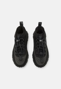 Scarpe sportive nere con upper in rete e materiale sintetico, suola testurizzata, lacci elastici e linguetta rinforzata per una facile calzata.