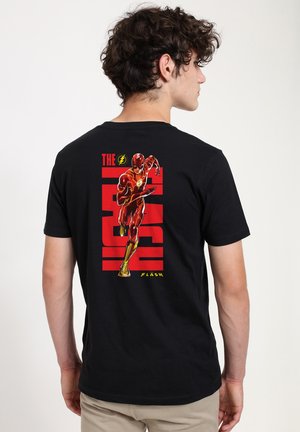 Czarny bawełniany t-shirt z kolorową grafiką przedstawiającą biegającą postać w czerwonym kostiumie, z napisem "THE FLASH" powyżej i akcentami w kolorze żółtym.