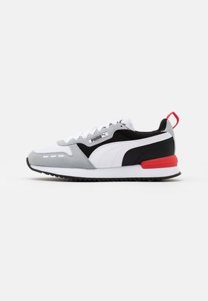 Puma sneakers featuring a mesh and suede upper in white, grey, and black, with a red accent on the heel and a rubber sole.