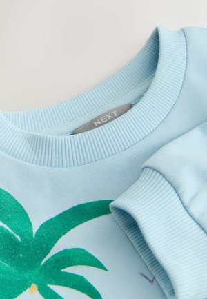 Sudadera azul claro con cuello acanalado, que presenta un gráfico de palmera verde con detalles de brillo. Tejido de algodón suave, diseño casual.