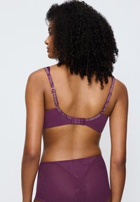 Purple lingerie set featuring a bra with intricate floral straps, a hook-and-eye closure, and matching high-waisted brief with a textured pattern.