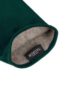 Grüne Wildlederhülle mit beigem Wollfutter, ausgestattet mit einem schwarzen Etikett mit der Aufschrift "ROECKL MÜNCHEN" im Inneren der Öffnung.