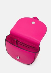 Malá jasně růžová kožená crossbody taška s otevřeným klopovým víkem, viditelným magnetickým uzávěrem, kapsou na zip a logem Valentino uvnitř.
