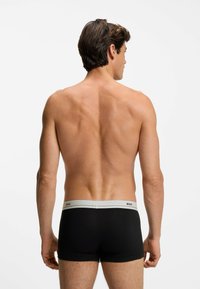 Boxer briefs neri con una vita grigia caratterizzata da lettering del marchio. Il tessuto appare liscio e la vestibilità è aderente al corpo.