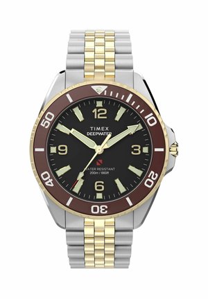 Timex Deepwater karóra fekete számlappal, arany és ezüst színű fémszíjjal, világító mutatókkal és barna, búvárkodásra jelölt forgatható lünettával.
