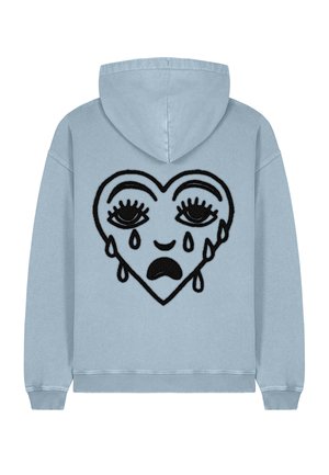 Sudadera azul claro con un diseño de corazón bordado en negro, con ojos cerrados, lágrimas y un ceño fruncido. Tejido suave y ajuste relajado.