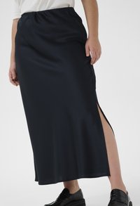 Gonna in satin di lunghezza media, di colore blu navy, con uno spacco laterale, caratterizzata da una vita elasticizzata e una texture liscia. Abbinata a scarpe nere.