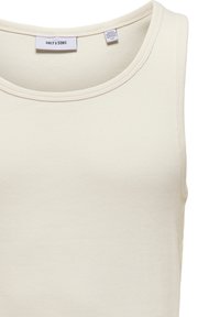 Top de tirantes acanalado color crema con escote redondo, hecho de una suave mezcla de algodón. Las etiquetas en el interior del cuello indican la marca y la talla.