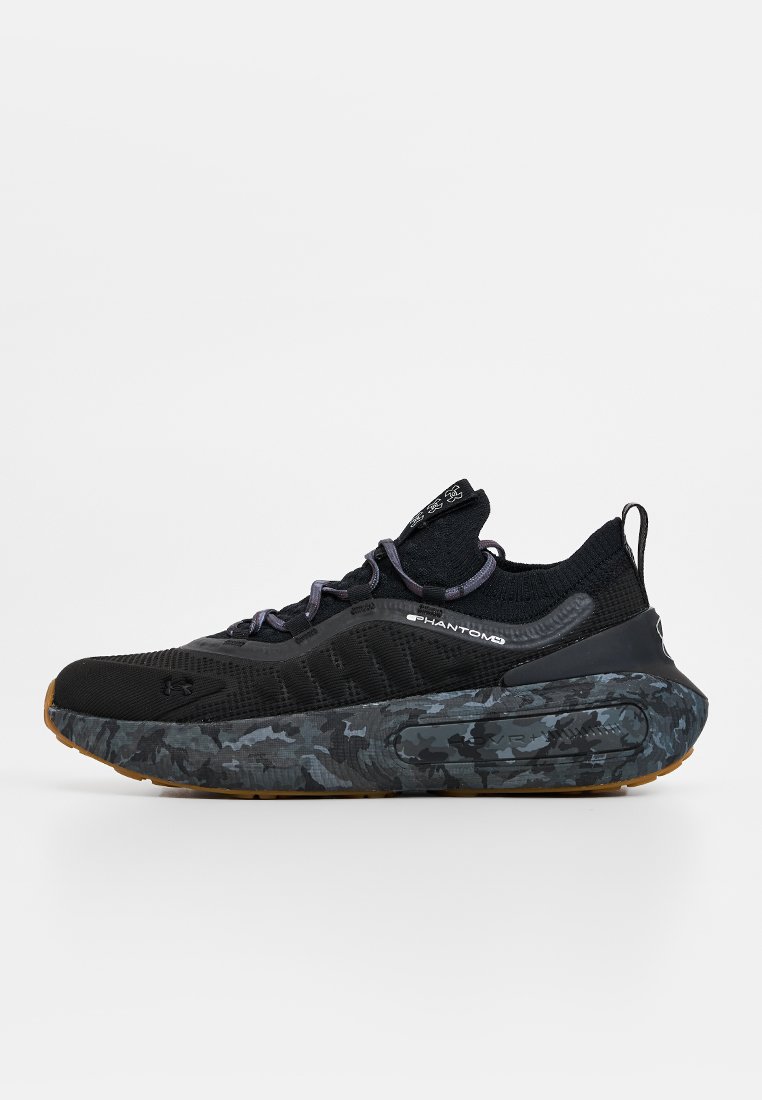 Zapato deportivo negro con parte superior de tejido texturizado, que presenta una suela con patrón de camuflaje y acentos morados, diseñado para la comodidad y el rendimiento.