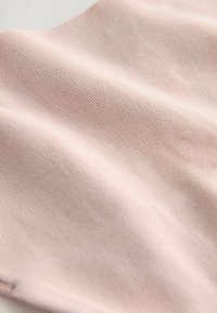 Jasnoróżowa tkanina o gładkiej fakturze i prążkowanym wzorze, ukazująca miękkie fałdy i jednolitą powierzchnię.