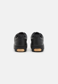 Sorte lædersneakers med quiltet tekstur, hævet logo på bagsiden og lysebrune detaljer på hælen. Gummisål med hexagonal design.