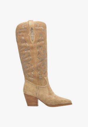 Tan suède cowboylaars met een spitse neus, versierd met zilverkleurige studs en intrigerende stiksels. Voorzien van een gestapelde hak en een hoge schacht.