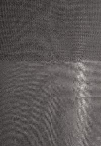 Svart tyg som visar ett strukturerat mönster med en subtil lyster. Materialet har en jämn yta och en mjuk, elastisk kvalitet.