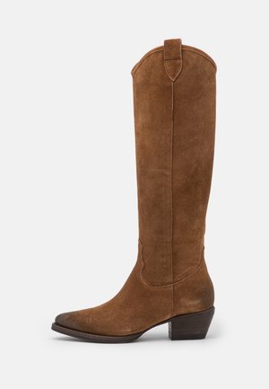 Botte montante de style western en daim marron, avec talon carré bas et languette de préhension en haut, vue de côté sur fond blanc.