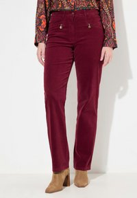 Pantaloni in corduroy bordeaux con due tasche frontali, accentuati da componenti metallici, e un design a gamba dritta. Tessuto testurizzato con una finitura morbida.