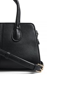 Melna ādas somiņa ar strukturētu formu, kurai ir augšējā rokturis un regulējams plecu siksna. Redzami zelta aksesuāri.