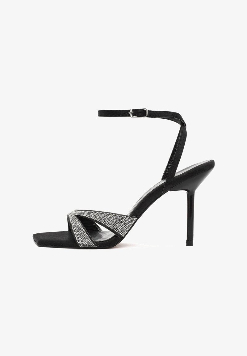 Sandalias de tacón alto negras con punta cuadrada, presentan tiras entrelazadas adornadas con rhinestones plateados y una delgada correa en el tobillo.