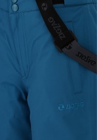 Blå vattentäta snöbyxor med en mjuk textur, sidofickor, knappdetaljer och ett justerbart svart bälte med "ZIGZAG"-logotypen.