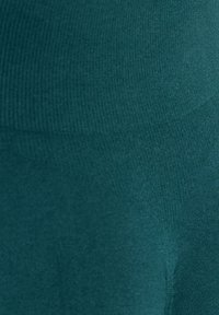 Turkusowe obcisłe legginsy o gładkiej, elastycznej strukturze. Tkanina ma delikatny wzór żebrowania, co zapewnia dopasowany wygląd.