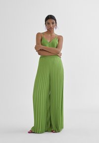 Groene geplooide broek met een bijpassende mouwloze top. Lichtgewicht, luchtige stof, met verticale plooien en een relaxte pasvorm.