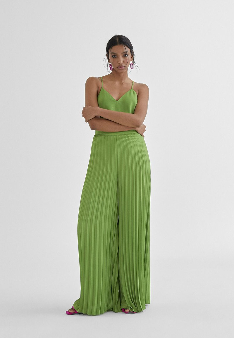 Groene geplooide broek met een bijpassende mouwloze top. Lichtgewicht, luchtige stof, met verticale plooien en een relaxte pasvorm.