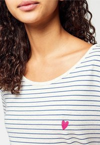 Randig kortärmad T-shirt i off-white med marinblå ränder, med ett litet rosa hjärta broderat på vänster bröstområde. Rundad halsringning.