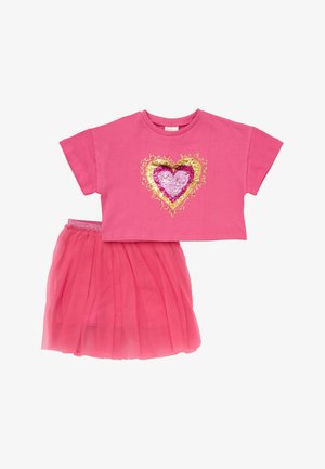 Vaaleanpunainen lyhythihainen croptop, jossa on paljetein koristeltu sydän, yhdistetty vastaavaan vaaleanpunaiseen tyllihameeseen, jossa on joustava vyötärönauha.