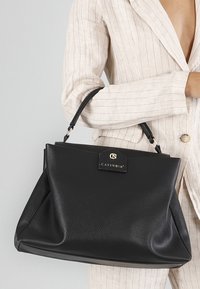 Borsa a mano in pelle nera con un design strutturato, caratterizzata da una placca del logo dorata, manici corti e una texture liscia.
