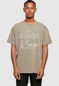 Barna, oversized pamut póló, fehér grafikával, amelyen az "BEACH Please" felirat olvasható egy nap és hullám mintával. Rövid ujjú.