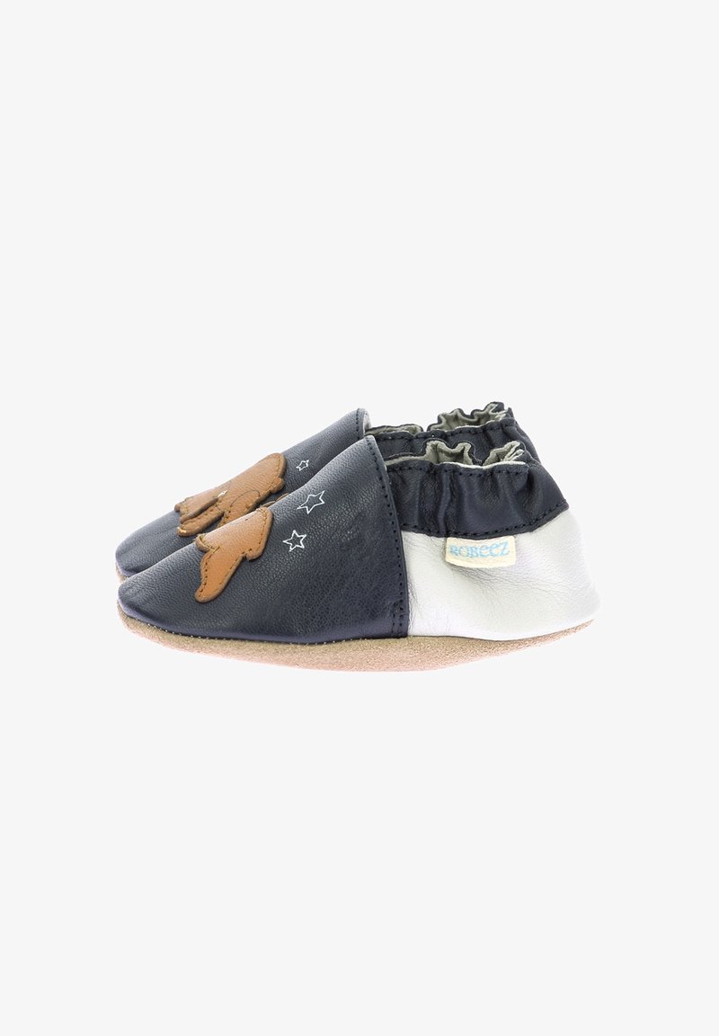 Scarpine in pelle per neonati con design a spacco. Materiali blu scuro e bianchi, dettagli marroni, caviglia elastica e motivo a stella sul lato.