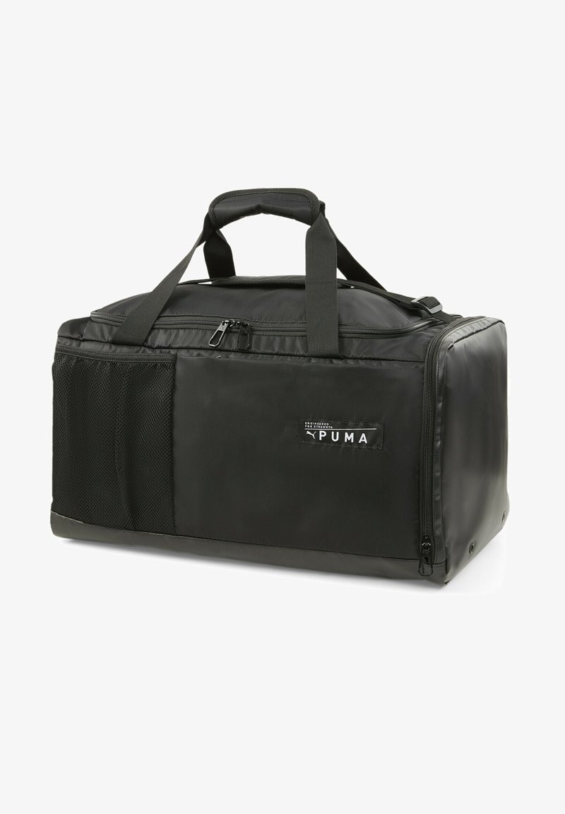 Bolsa de viaje negra hecha de nylon duradero, con un compartimento principal con cremallera, un bolsillo lateral de malla y dos asas robustas. Logo de Puma visible.