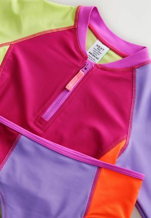 Viacfarebný rash guard s ružovými, zelenými, fialovými a oranžovými sekciami; mäkký, elastický materiál s predným zipsom a šitými detailmi.