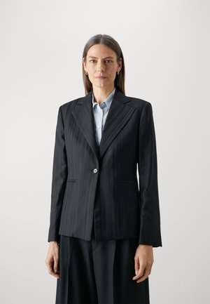 Blazer a righe nere realizzato in un tessuto liscio, con chiusura a un bottone, colletto a rever e tasche frontali. Vestibilità tailored.