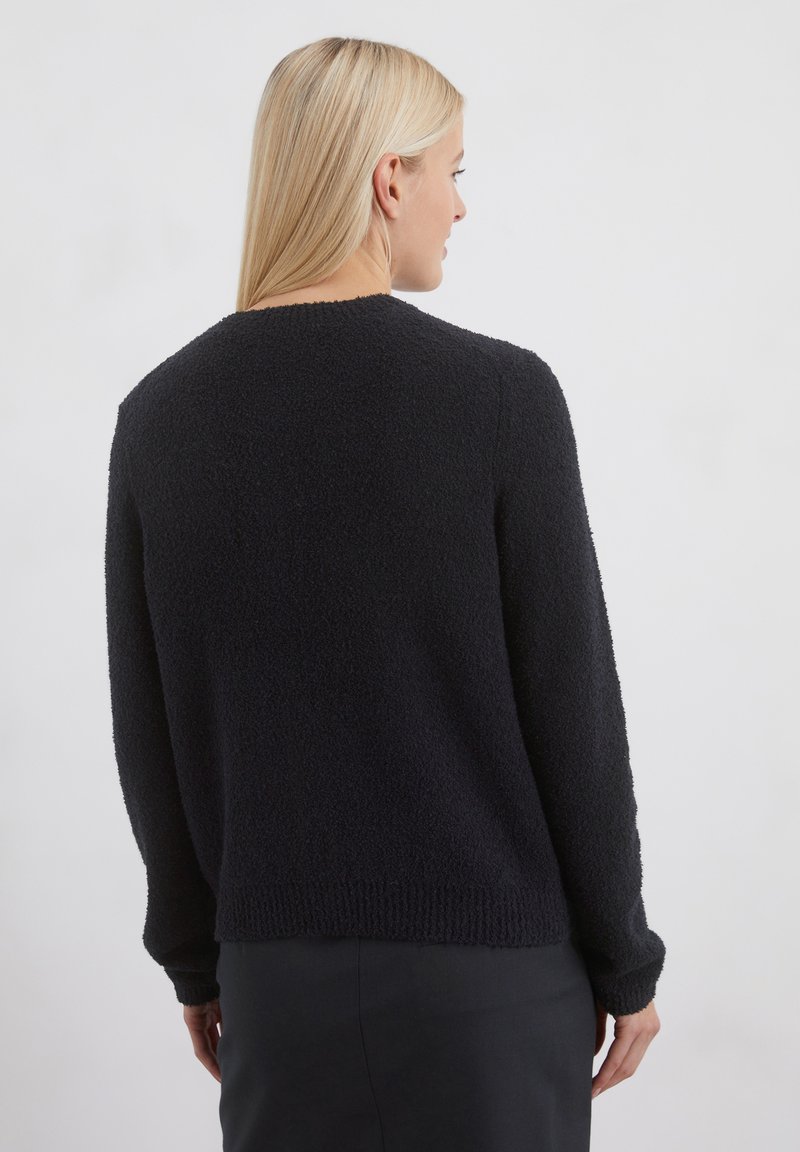 Schwarzer strukturierter Pullover mit rundem Halsausschnitt, langen Ärmeln und gerippten Bündchen sowie Saum. Weiches, flauschiges Material mit einer lockeren Passform.