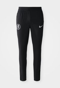 Melnas sporta bikses ar ribotu tekstūru, kurām kreisajā kājā ir balts FC logo un labajā pusē pelēks Nike zīmols.