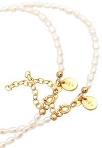 Perlenkette mit unregelmäßig geformten weißen Perlen und goldfarbener Hardware. Verfügt über einen Kettenverlängerer und zwei runde Anhänger, die den Metallgehalt anzeigen.