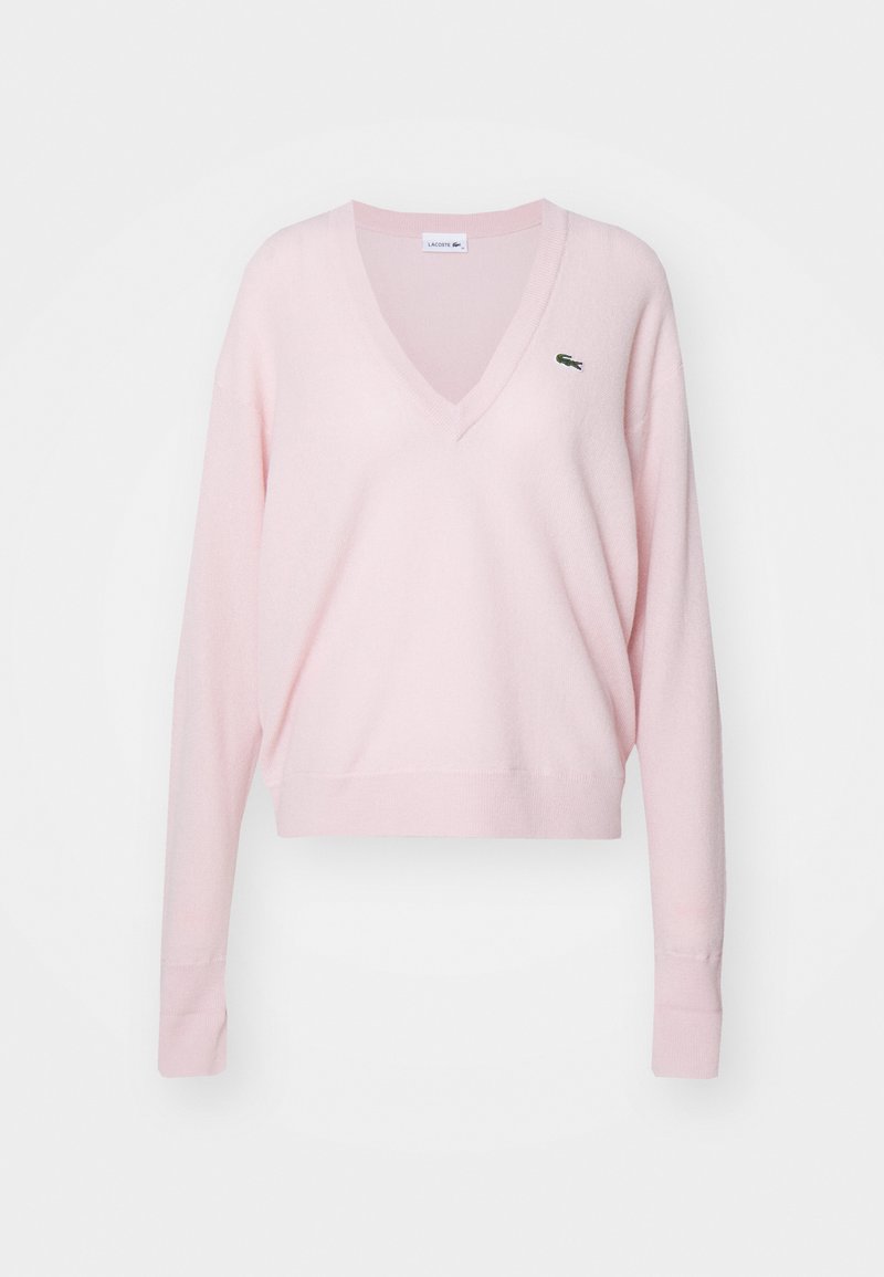 Pull V en laine rose clair, à manches longues, avec des poignets et un ourlet côtelés, présentant un petit logo vert sur le côté gauche de la poitrine.