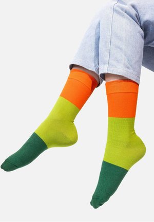 Kolorowe skarpetki sięgające do kolan z poziomymi paskami w odcieniach pomarańczowym, jaskrawej zieleni i ciemnej zieleni. Gładka tekstura z prążkowanymi ściągaczami.