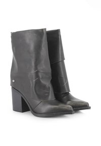 Botas de cuero negras hasta el tobillo con un diseño holgado, punta afilada y tacones de bloque de 4 pulgadas; cuenta con un discreto acento metálico en el costado.