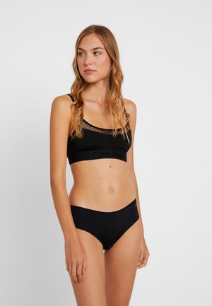Black sports bra with mesh detailing and a textured band featuring the Calvin Klein logo, paired with simple black hipster briefs.