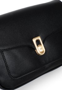 Zwarte leren tas met textuur en een gouden sluiting. Heeft een rechthoekige vorm en precieze stiksels langs de randen voor duurzaamheid.