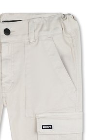 Pantaloni cargo beige in cotone, con chiusura a bottone, tasche frontali e una tasca applicata sul lato con il logo DKNY.
