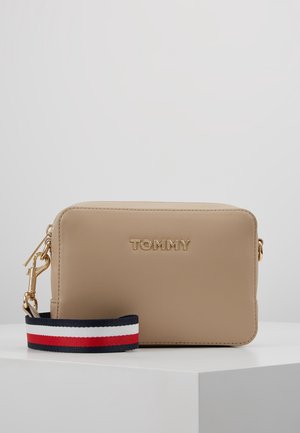 Beżowa prostokątna torba na ramię z złotym logo "TOMMY" i odpinanym paskiem w czerwone, białe i granatowe paski.