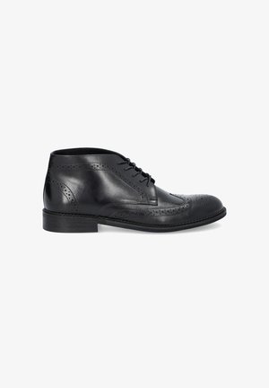 Czarne skórzane botki za kostkę z perforowanym detalem brogue, okrągłym noskiem i płaską podeszwą. Posiadają zapięcie na sznurówki i gładką fakturę.