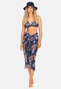 Granatowy bikini w kwiaty z różowymi i niebieskimi wzorami liści, zestawione z dopasowaną, przezroczystą spódnicą owiniętą w talii oraz granatowym kapeluszem przeciwsłonecznym.