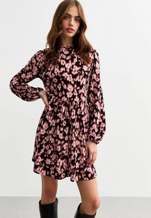 Zwart jurkje met korte mouwen en een roze bloemenpatroon. Heeft een getailleerde taille, een vloeiende rok en ruches aan de mouwen met een lichte puff. Zwarte knie-hoge laarzen.