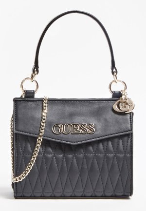 Sac à main en cuir matelassé noir avec logo GUESS doré, chaîne dorée et poignée courte sur fond blanc.