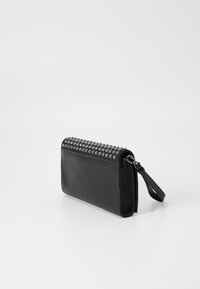 Black leather clutch with studded accents along the top. Features a zip closure and a detachable wrist strap. Smooth texture.